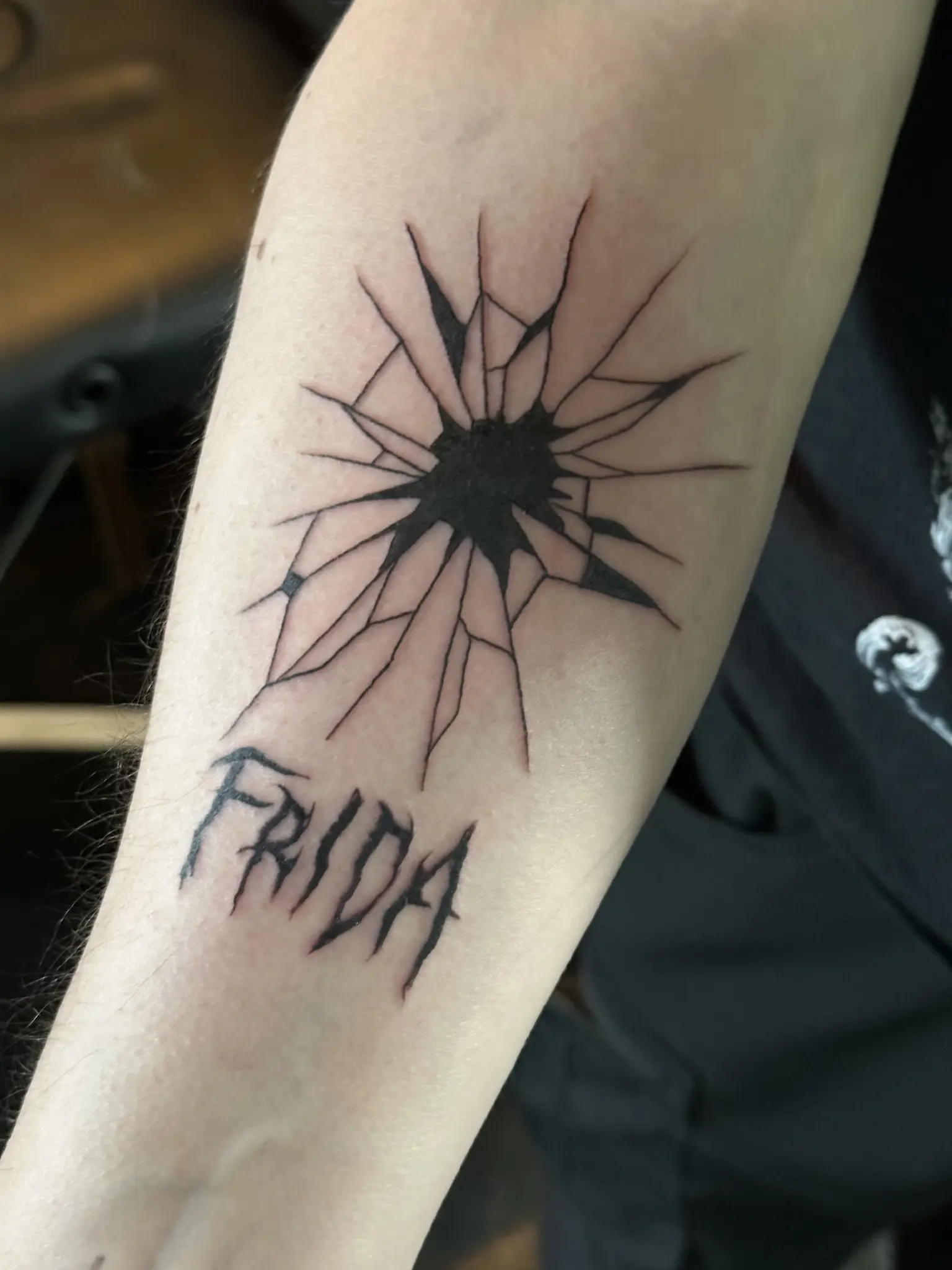 kuvassa tatuoitu käsivarsi, joka kuvastaa särkynyttä lasia. Alapuolella nimi Frida, joka kuvaa henkilöä, joka minut vaariutti.